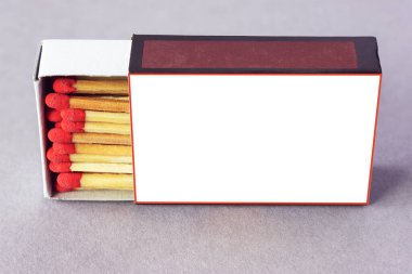 Gri arkaplanda kırmızı kibrit başlıklarının olduğu kağıt kibrit kutusu, metin için boşluk