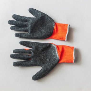 Gri arka plana bakan siyah lateks kaplı bir çift kırmızı eldiven.