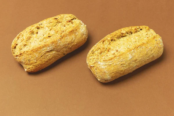 Close-up view of two small fitness buns, a healthy snack or breakfast option, placed on a brown background. The concept of healthy eating, fitness and balanced nutrition.
