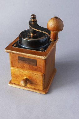 Gri arka planda kahve çekirdeklerini öğütmek için kullanılan eski model el yapımı kahve öğütücüsü.