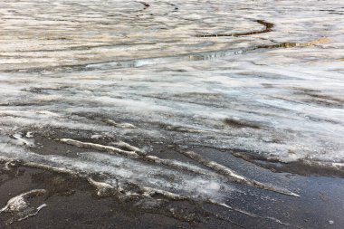 Bahar, eriyen kar ve buzu getirir ve arka plan olarak sıcak güneşin altında asfalt bir alanda güzel bir sahne yaratır.