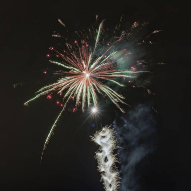 Bir havai fişek aydınlık ve parlak ışıkla karanlık gökyüzünü aydınlatıyor.