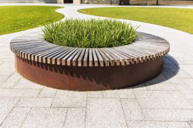 Yeşil bitkilerle dolu yuvarlak ahşap bir bank. Açık havada rahatlamak ve oturmak için mükemmel. Bahçenize ya da avlunuza biraz doğa katar. Dayanıklı ve dayanıklı ahşap. Şık ve işlevsel.