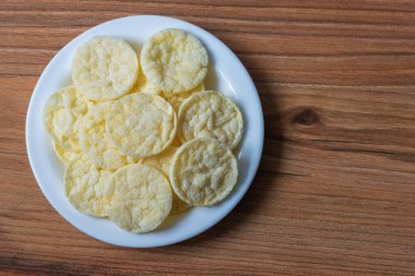 Çam masa yüzeyinde tabakta peynir aromalı pirinç cipslerinin üst görüntüsü
