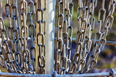 Yakın plan çekimde, diskten sarkan metal zincirler, sporda frizbileri yakalamak için tasarlanmış..