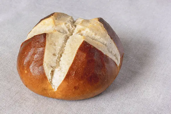 Taze pişmiş geleneksel Bavyera Laugenbrot. Bavyera ev yapımı yarı bitmiş ekşi ekmekli, kumaştan keten masa örtüsüne yakın plan.
