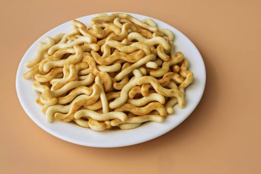 Turuncu arka plandaki bir tabakta büyük bir organik kraker yığını.