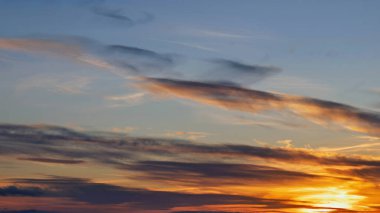 Günbatımı gökyüzünde sıcak renkler bırakır, bulutları turuncu, pembe ve mavi tonlarında aydınlatır..