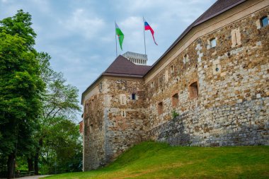 Slovenya 'daki Ljubljana şatosunda dramatik bir gökyüzüne karşı bayraklar