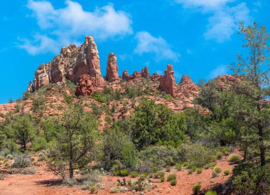 Mavi gökyüzü ve kabarık bulutlar Sedona AZ 'de Margs boyunca kırmızı kayaları dengeliyor.