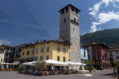 PISOGNE, ITALY, 22 HAZİRAN 2024: İtalya 'nın Lombardiya kentindeki Pisogne gölündeki Piazza Umberto I ve Torre de Vescovo' nun yaz manzarası. Pisogne, Iseo Gölü 'nde popüler bir turizm merkezidir.