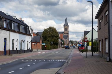 AALST, BELGIUM, 3 EKİM 2024: Herdersem 'in merkezindeki kilise ve binalarla ana yolun görüntüsü. Herdersem, Aalst ilinin bir ilçesidir..