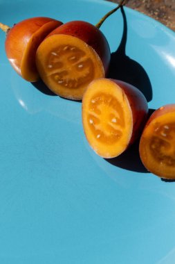 Dilimlenmiş Tamarillo meyvesinin (Solanum betaceum) karşıt mavi bir plaka üzerinde fotokopi alanı ile yakın plan görüntüsü.