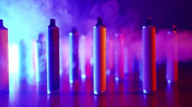 Neon Lighting ve Smoke 'ta bir sürü e-sigara ve Vapes var. Kötü alışkanlık kavramı. Modern Tütün Ürünleri Alternatifi. Nikotin Bağımlılığı. Yavaş Hareket.