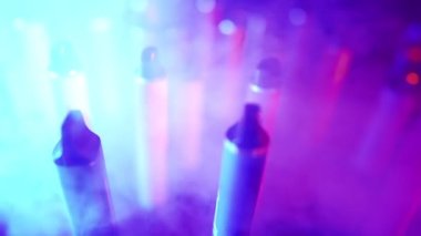 Neon Lighting ve Smoke 'ta bir sürü e-sigara ve Vapes var. Kötü alışkanlık kavramı. Modern Tütün Ürünleri Alternatifi. Nikotin Bağımlılığı. Yavaş Hareket.