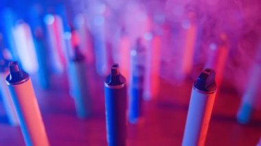 Neon Lighting ve Smoke 'ta bir sürü e-sigara ve Vapes var. Kötü alışkanlık kavramı. Modern Tütün Ürünleri Alternatifi. Nikotin Bağımlılığı. Yavaş Hareket.