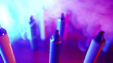Neon Lighting ve Smoke 'ta bir sürü e-sigara ve Vapes var. Kötü alışkanlık kavramı. Modern Tütün Ürünleri Alternatifi. Nikotin Bağımlılığı. Yavaş Hareket.