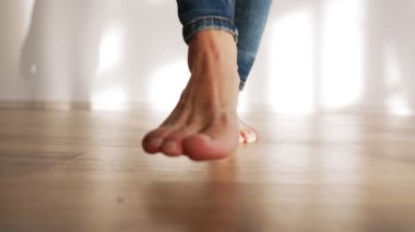 Beautiful Female Bare Feet Walk along the Parquet Floor of the House in Sunshine. Slow Motion.