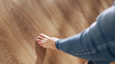 Beautiful Female Bare Feet Walk along the Parquet Floor of the House in Sunshine. Slow Motion.