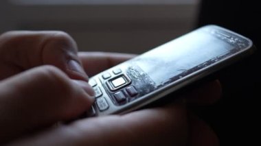 Close-up male hands are using an old push-button mobile phone from the past. Technology development concept.