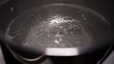 Water is boiling in a pot on the stove. Boiling water in slow motion.