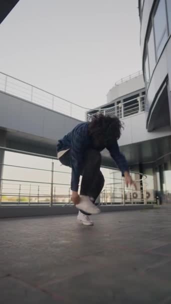 縦型ビデオ スタイリッシュな男性ストリートダンサー都市の背景にヒップホップとブレースダンスを踊る ファッショナブルな服の現代人は街の通りでダンスをします スローモーション — ストック動画