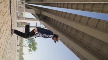 Dikey Video, Modern Adam Şehir Caddesinde Dans Ediyor. Güneşli bir günde modern koreografiyle dans eden modacı. Yavaş Hareket.