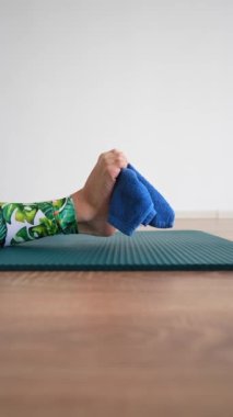 Dikey videoda zayıf bir kadın spor minderinde güzel ayaklar için egzersiz yapıyor. Yakın çekim, tanınmayan kişi..