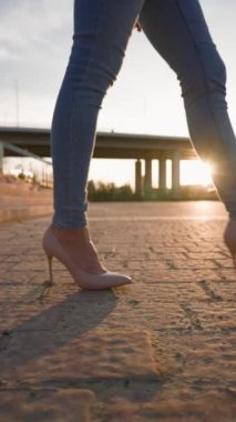 Dikey Video, Yüksek Topuklu İş Kadını ve Sunset Light 'taki Şehir Parkı' nda Yürüyen Kot Pantolon. Güzel İnce Kadın Bacakları Sunlight 'taki Tiles City Caddesi' nde yürüyor. Tanınmayan Kişi, Yavaş Hareket