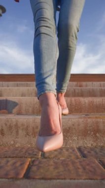 Dikey Video, Yüksek Topuklu Ayakkabılı İnce Kadın Bacakları Şehir Parkı 'nda Günbatımı Yürüyüşü. Gün batımında Güzel Bacaklı Kadın Merdivenlerden Aşağı Gidiyor. Tanınmayan kişi. Yavaş Hareket.