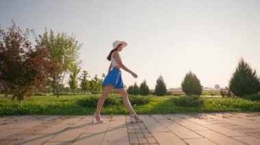 Mavi Şortlu Zarif Kadın ve Beyaz Şapkalı Kadın, Gün batımında Bacağını Ayırır. Havalı esnek bacaklı atletik zayıf kız bacağını harika kaldırıyor. Yavaş Hareket.
