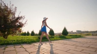 Mavi Şortlu Zarif Kadın ve Beyaz Şapkalı Kadın, Gün batımında Bacağını Ayırır. Havalı esnek bacaklı atletik zayıf kız bacağını harika kaldırıyor. Yavaş Hareket.
