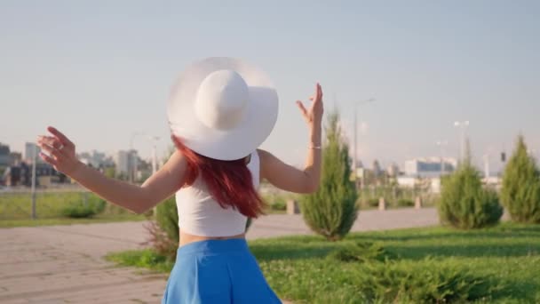 성공으로 화이트 모자에 만족한 호리호리한 소녀는 공원에 그리고 복지를 느낀다 — 비디오