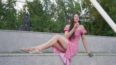 Açık havada sabun köpüğü üfleyen gözlüklü güzel kadın. Yetişkin Çağı 'ndaki Yavaş Çocukluk Çekimleri. Güneş Işıkları Altında Eğlence. Çocuksu Oyun Oynayan Mutlu Kızın Portresi. 