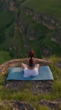 Dikey Video, Sports Girl Sunrise sırasında meditasyon yapıyor. Dağlarda spor yapan atletik kadın, Lotus Yoga pozisyonunda oturuyor. Sağlıklı Yaşam Tarzı ve Refah, Zenizm Konsepti. Yavaş Hareket.
