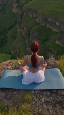 Dikey Video, Sports Girl Sunrise sırasında meditasyon yapıyor. Dağlarda spor yapan atletik kadın, Lotus Yoga pozisyonunda oturuyor. Sağlıklı Yaşam Tarzı ve Refah, Zenizm Konsepti. Yavaş Hareket.