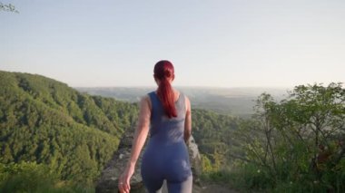 Spor Önlüklü Sıska Atletik Kadın Arka plan Güzel Doğal Manzarası 'nda bir dağın tepesindeki tepeye koşuyor. Top Mountain 'daki Mutlu Kız Zafer ve Başarı Hissediyor. Yavaş Hareket.
