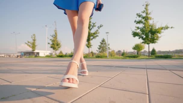 Vackra Kvinnliga Smala Ben Vita Högklackade Sandaler Promenera Genom Stadsparken — Stockvideo