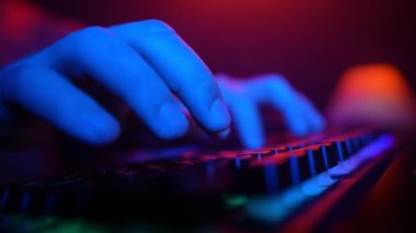 Male Hands Typing on a Computer Keyboard in Neon Lighting. Unrecognizable Guy Working on a Laptop at Night. Concept of Hackers and Cyber Crimes or Cyberspace.