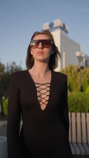 穿着黑色紧身衣 步履自信的有诱惑力的瘦女人沿着城市街道走着 时尚与美的概念 垂直录像 慢动作 — 图库视频影像