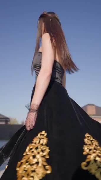 美丽的公主 头戴皇冠 穿着黑色衣服 金色图案 在艳阳天纺纱 时装模特在形象历史皇后中的位置 垂直录像 — 图库视频影像