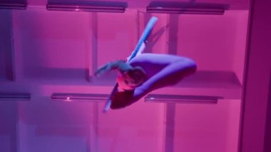 Atletik Güzel Kız Aerialist, Havadan Halka 'da Bir Dalavere Gösteriyor. Purple Neon Lighting, Slow Motion 'da. Alt açı.