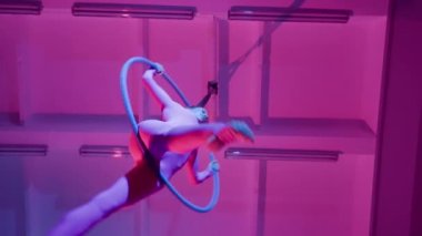 Atletik Güzel Kız Aerialist, Havadan Halka 'da Bir Dalavere Gösteriyor. Purple Neon Lighting, Slow Motion 'da. Alt açı.