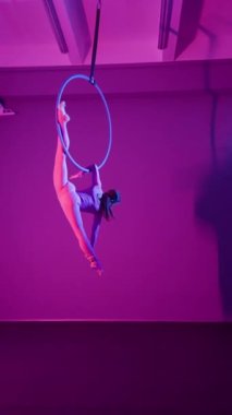Atletik Güzel Kız Aerialist, Havadan Halka 'da Bir Dalavere Gösteriyor. Mor Neon Işıklandırma 'da. Dikey video, Yavaş Hareket.