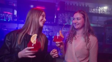 İki Kız Arkadaş Bir Neon Işıklandırma Gece Kulübü 'nde Barın Yanında Ellerinde Kokteyllerle Dans Ediyor. Gece Barındaki Partide Eğlenen Mutlu Kadınlar. Yavaş Hareket.