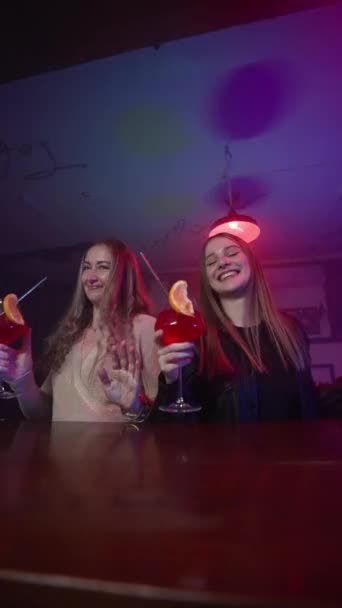 Вертикальне Відео Дві Дівчини Танцюють Коктейлями Руках Біля Барної Стійки — стокове відео