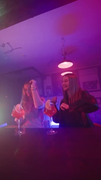 Вертикальное Видео Две Подруги Танцуют Коктейлями Руках Возле Барной Стойки — стоковое видео