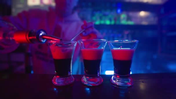 Guy Barman Nalewa Koktajl Alkoholowy Trzech Przezroczystych Kieliszków Blacie Blue — Wideo stockowe
