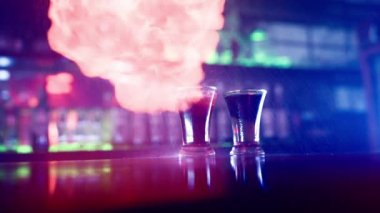 Bar tezgahında bir bardak Alkollü İçki. Barmen bir gece kulübünde bir bardak Cocktail 'i ateşe vererek içki hazırlıyor. Neon Blue Lighting 'deki bar. Yavaş Hareket.