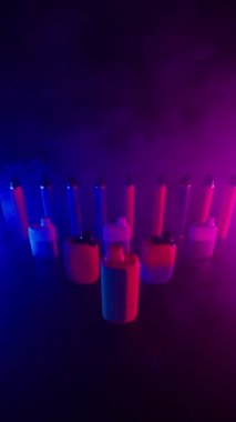 Bir sürü Vapes ve Electronic Cigarettes Neon Light Dark Reground. Nikotin Bağımlılığı ve Sağlık Zararı kavramını kabul et. Akciğer kanseri. Kötü alışkanlık. Tütün endüstrisi. Sağlıksız yaşam tarzı. Dikey Video, Yavaş Hareket